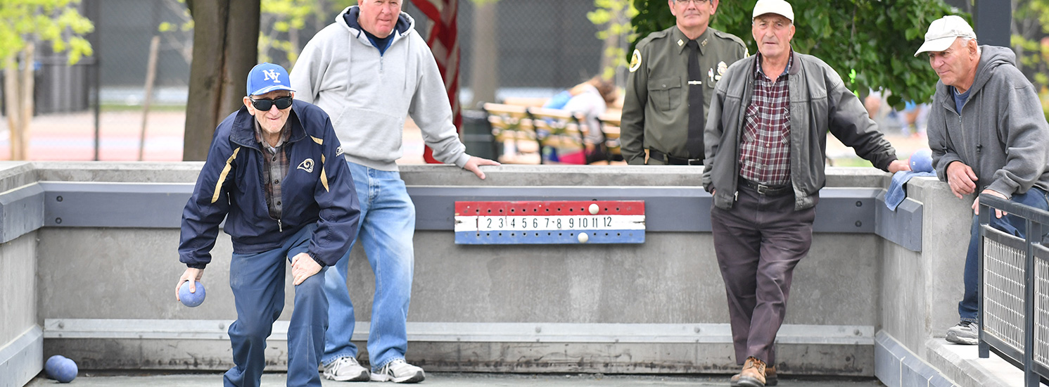 A group of older bocce ball players on a court.