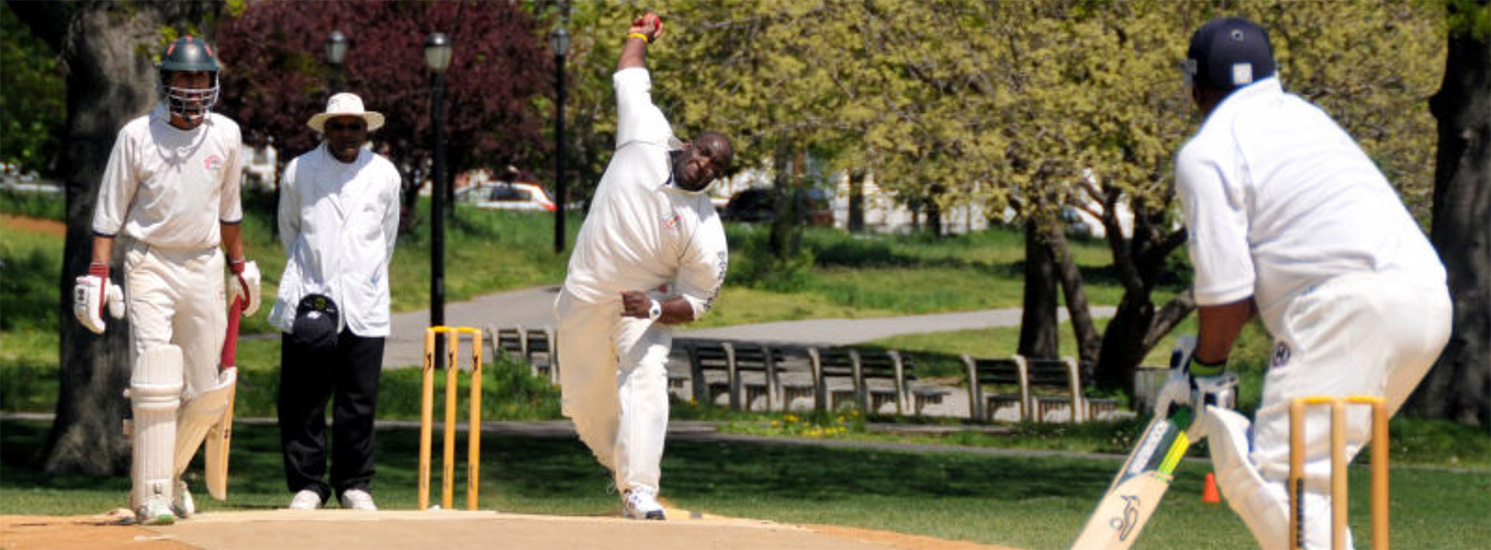 A bowler throwing a cricket ball towards a batter.