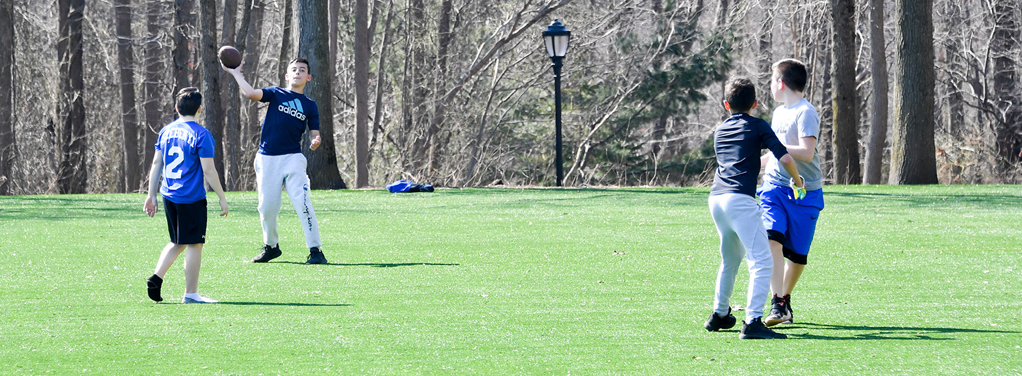 Children playing football on a turf field.