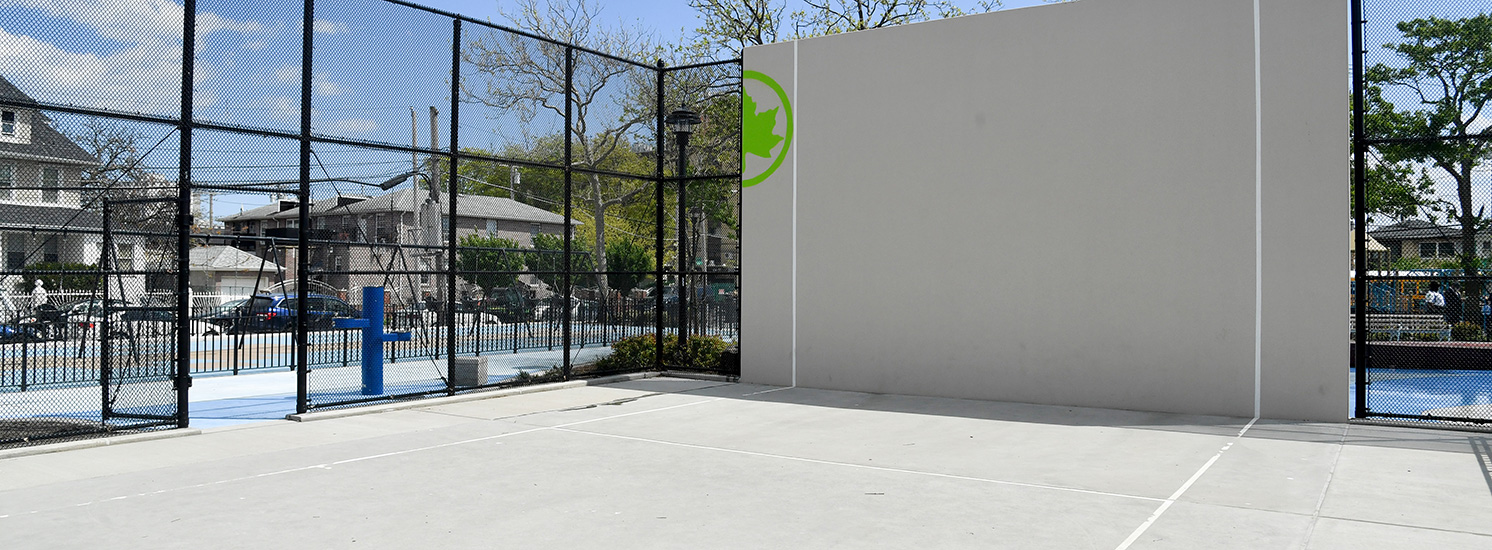 A handball court with the NYC Parks logo painted on the side.