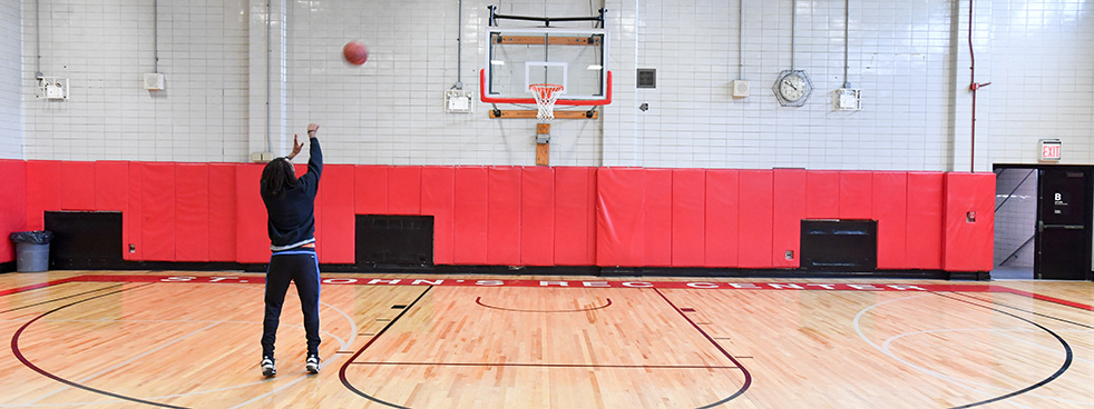 A player shooting a basketball in a recreation center gym.