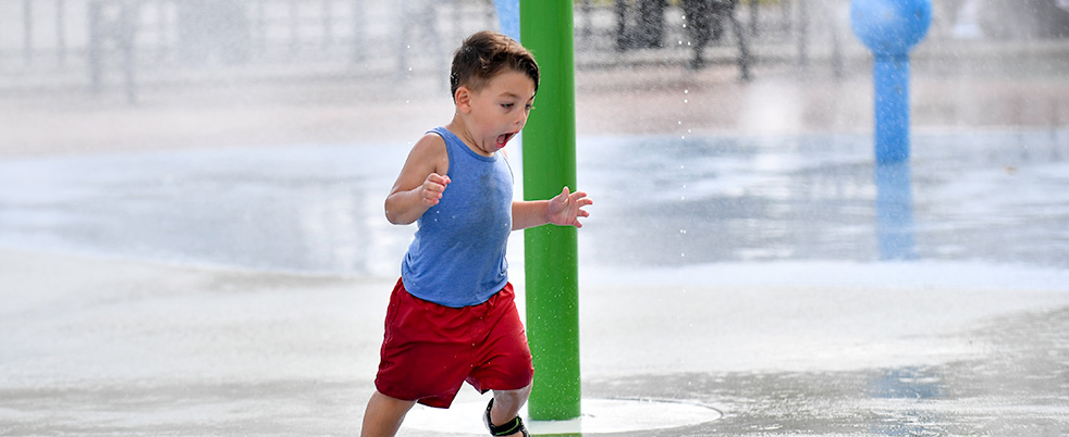 An excited child runs through a spray shower.