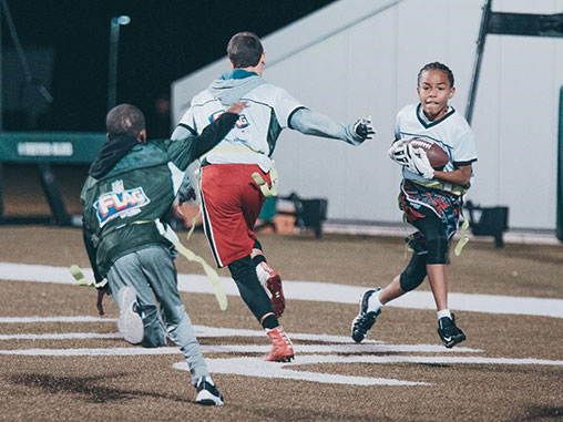 Three boys playing flag football