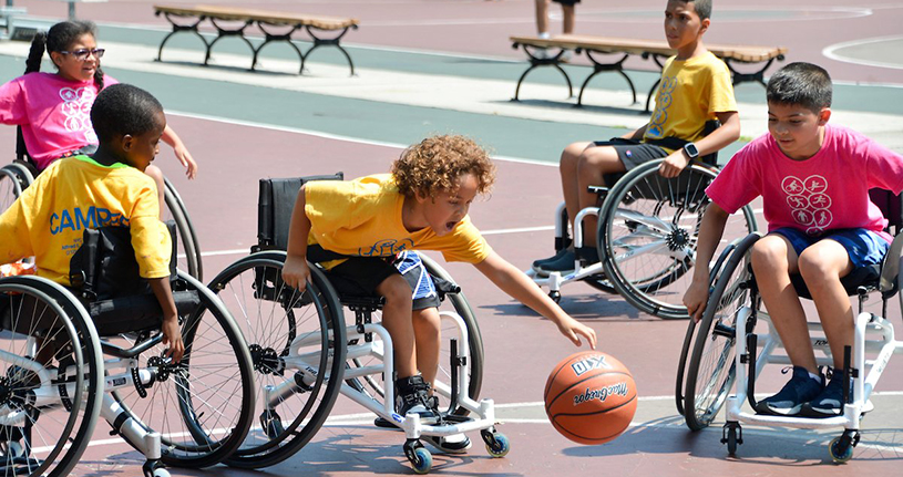 Kids play Wheelchair Basketball as part of their outdoor sports activities at summer camp.