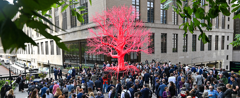 A crowd of people gathered around a sculpture.