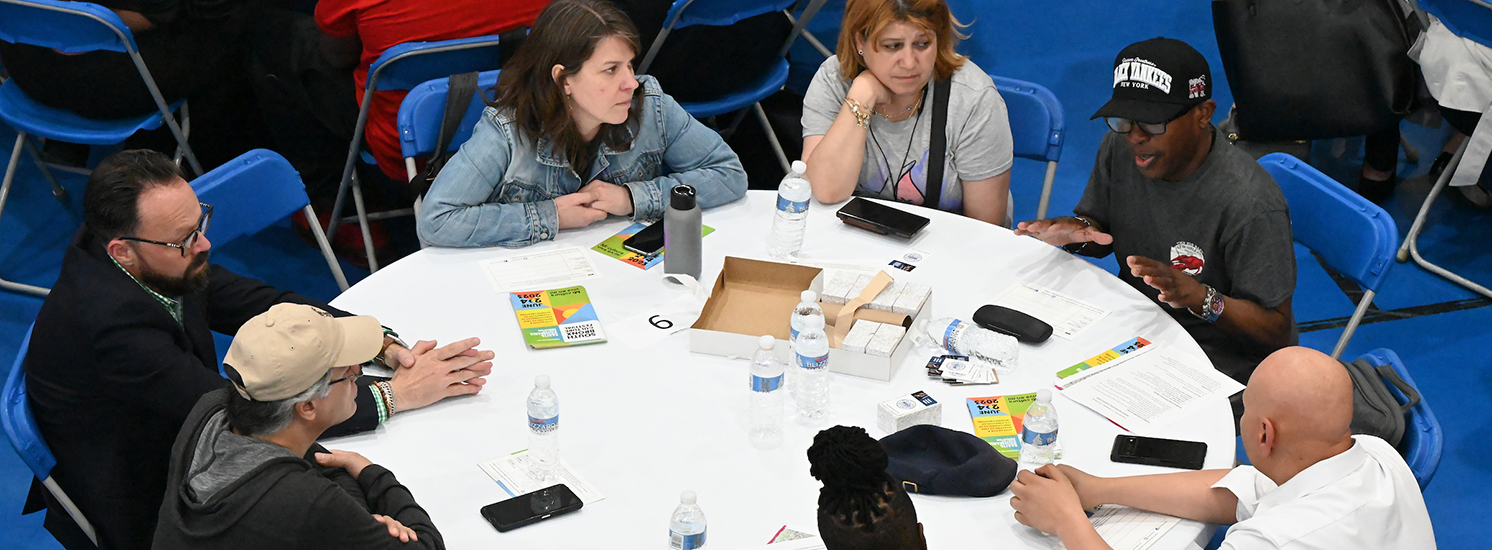 A diverse set of neighbors sitting around a table and coming together to have a discussion.