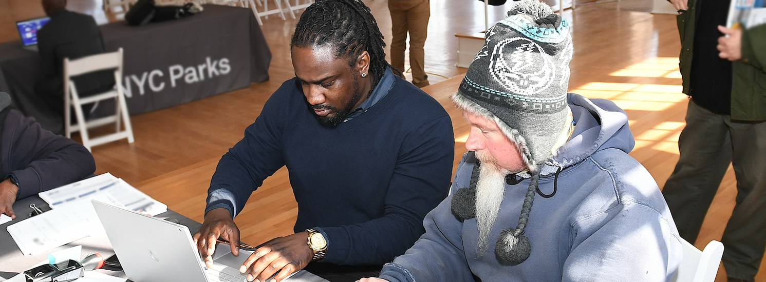 Two men appear to be sharing a computer to learn more information. They are of different ethnic backgrounds and ages.