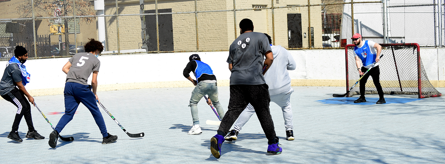 Young New Yorkers play street hockey on a city rink.