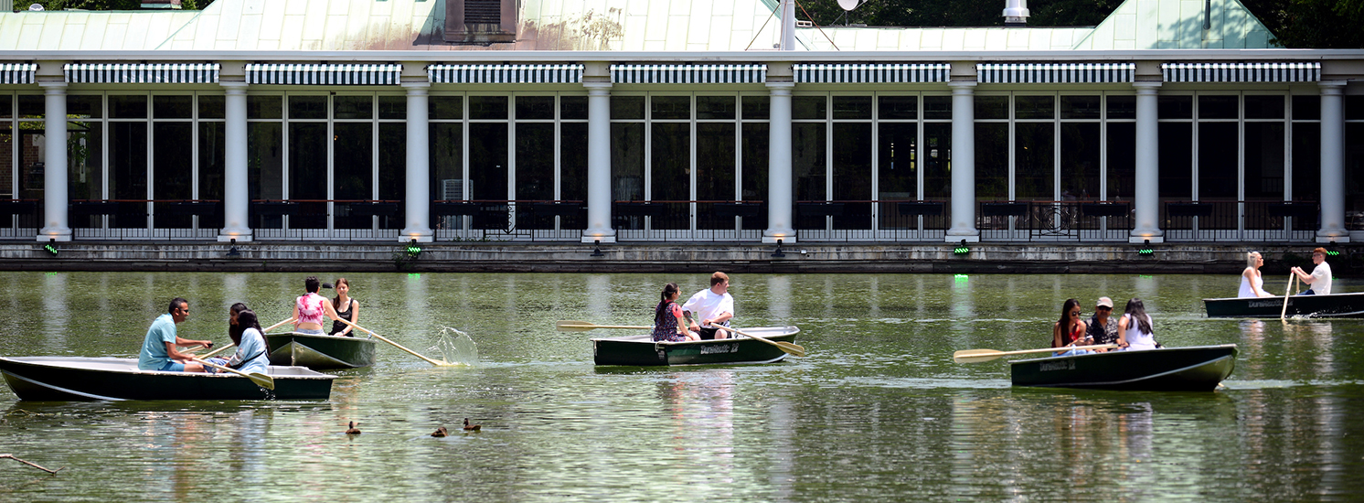 Groups of boaters rowing in a lake near the iconic Central Park Boathouse.