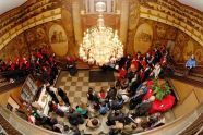 The choir sings carols for a gathered crowd in the building's lobby 